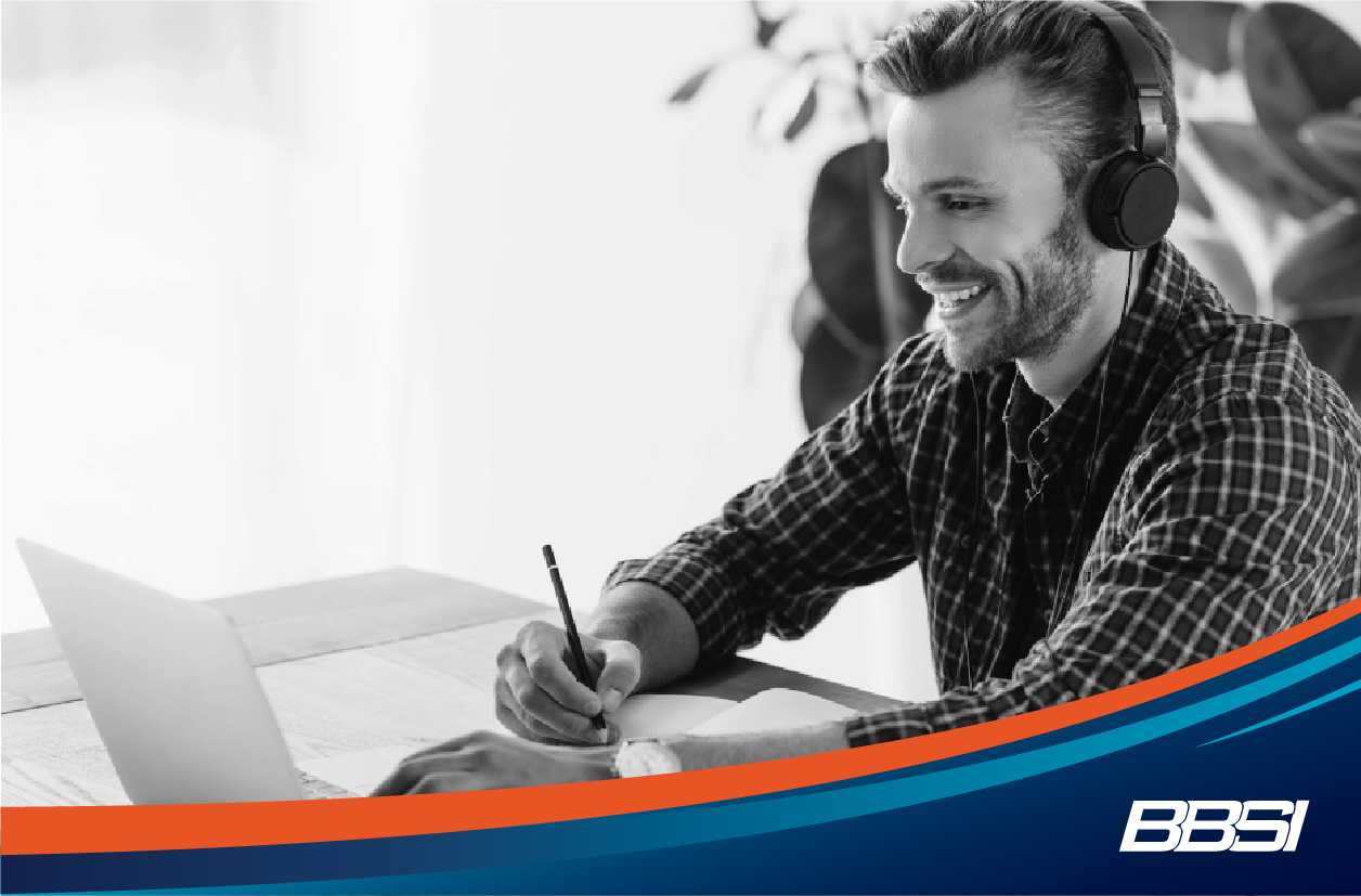 Man taking notes while listening to a webinar hosted by an insurance broker