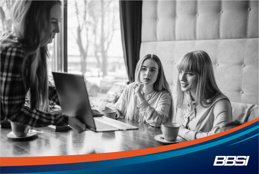 Three women work on a marketing strategy for their small business in a coffee shop