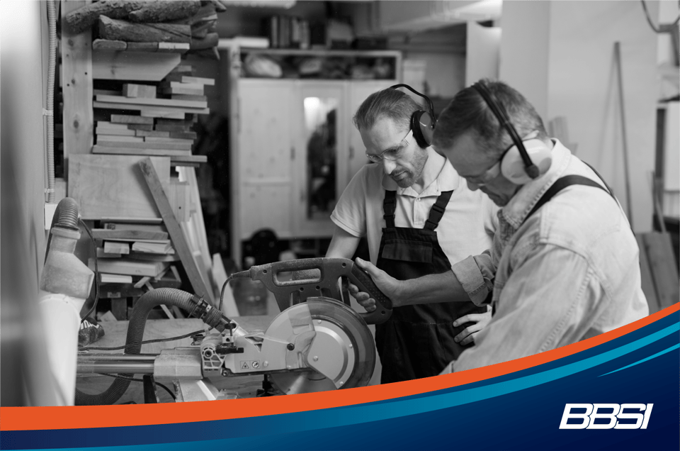 Carpenter cutting wood using disk saw while mentoring new employee