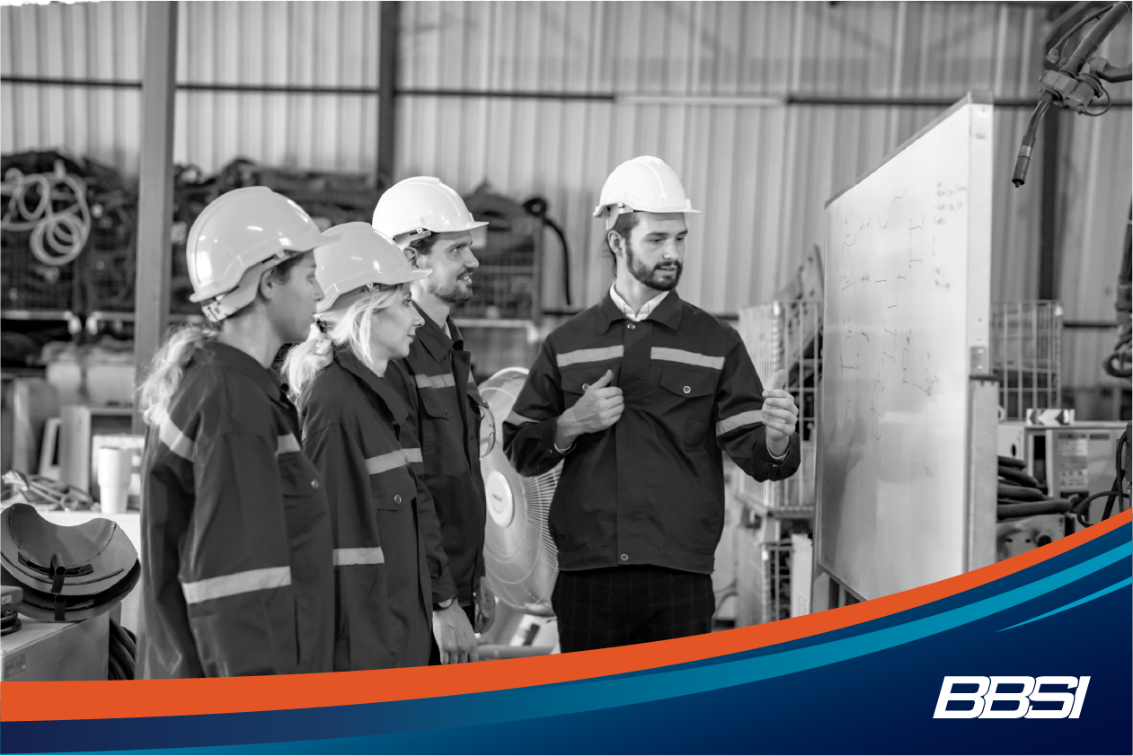 Employees in PPE meeting in front of a white board