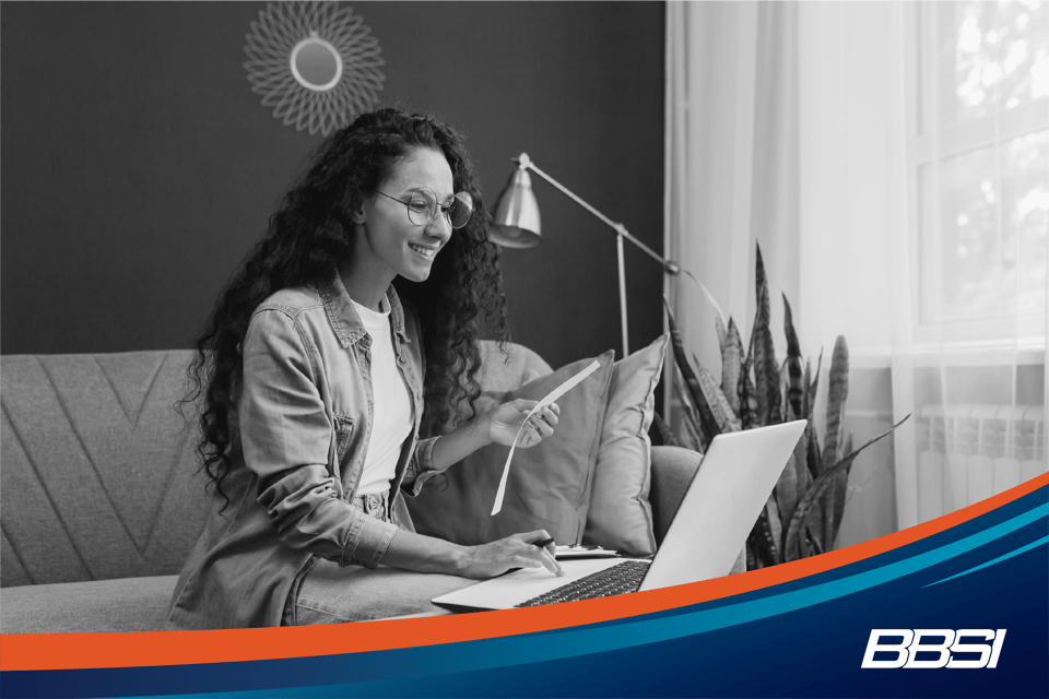 Woman with glasses using her laptop while working on her business's payroll schedule