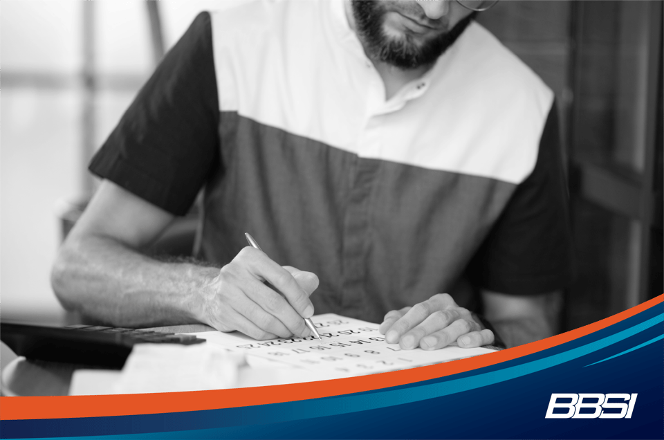 Business owner working on his payroll schedule while wearing a striped shirt sitting at desk. 