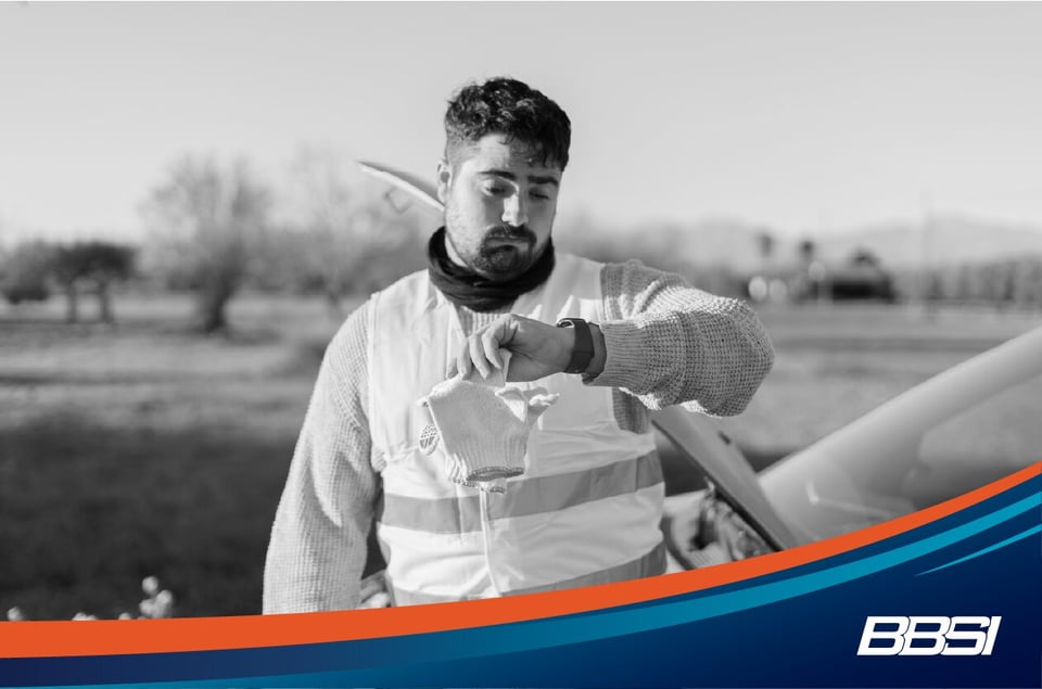 Man in saftey vest checks his watch to make sure he is tracking his time at work properly