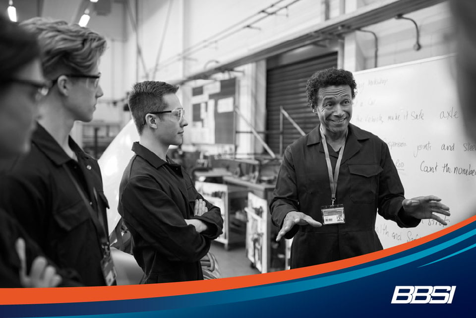 Mechanic teaching a group of younger mechanics in a workshop encouraging employee engagement