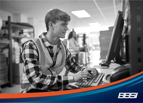 a young man in a warehouse at a computer using hr technology