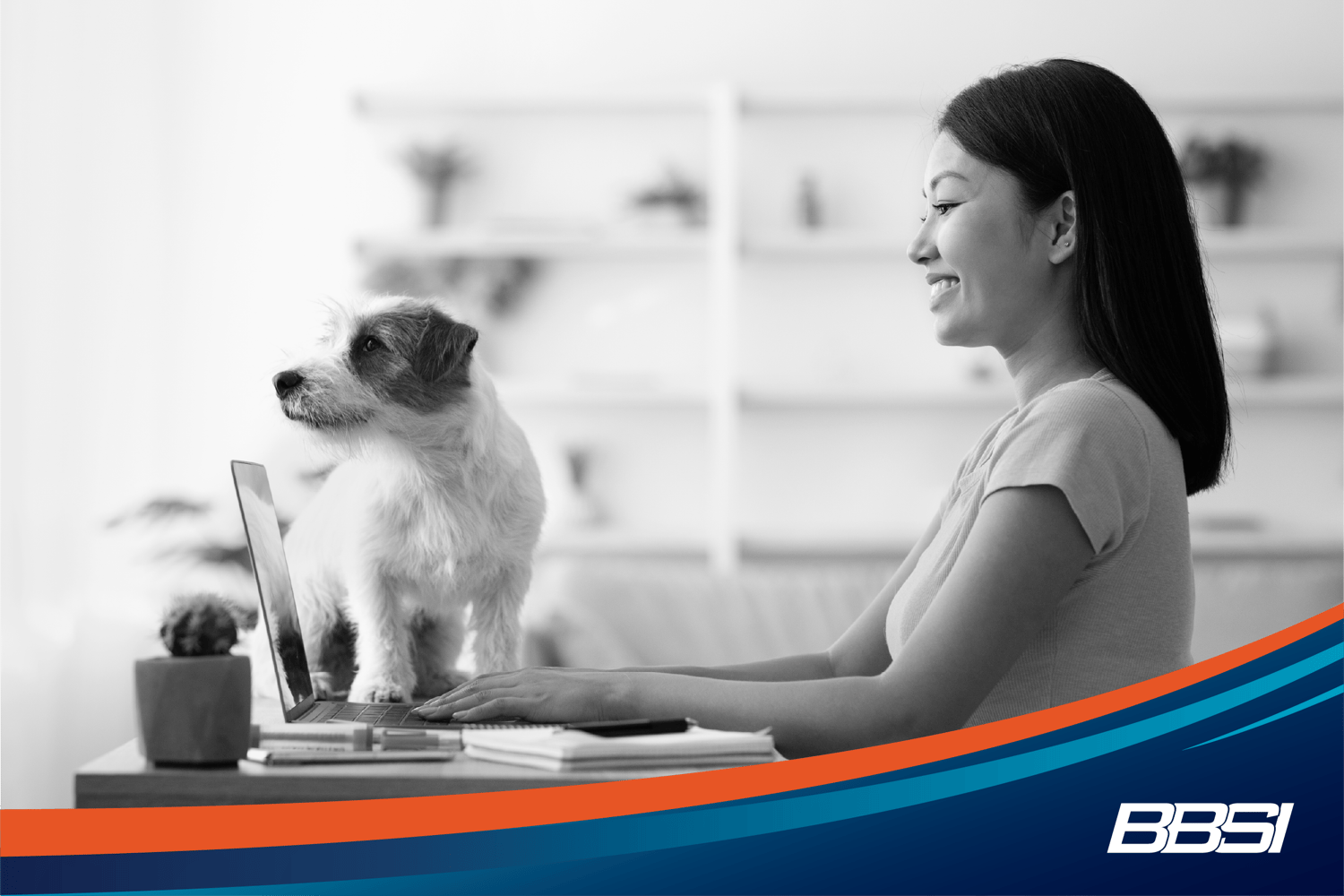 A woman works on her laptop from home with her brown and white jack russell terrier. 