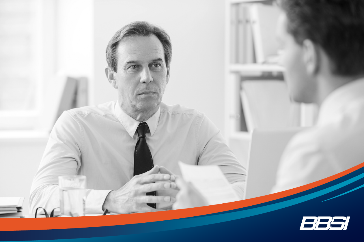 Man sitting across from an employee at his desk that he is about to let go