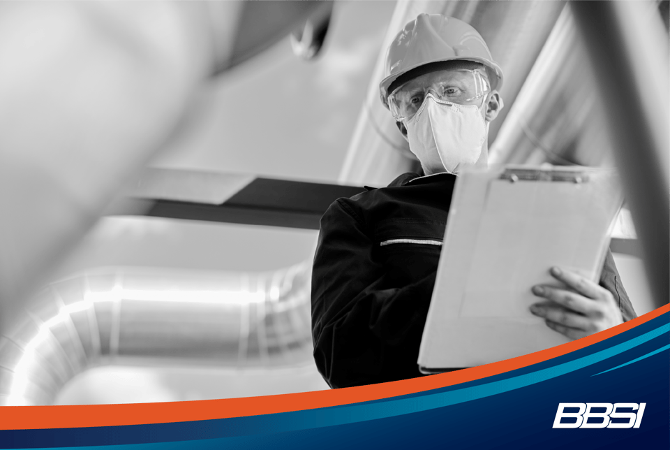 Construction site inspector with PPE taking notes on a clipboard