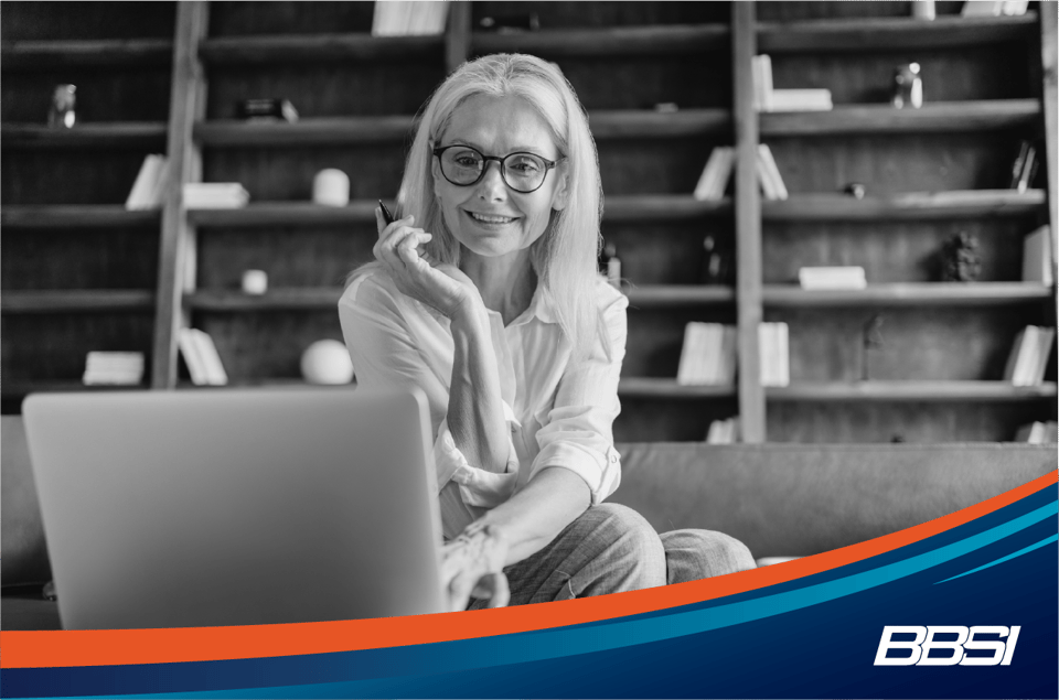 Woman with blonde hair and glasses looking at her computer in her office.