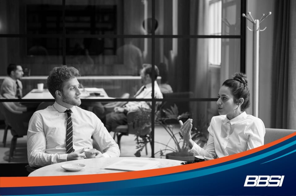 a man and woman having a discussion over coffee in an office.