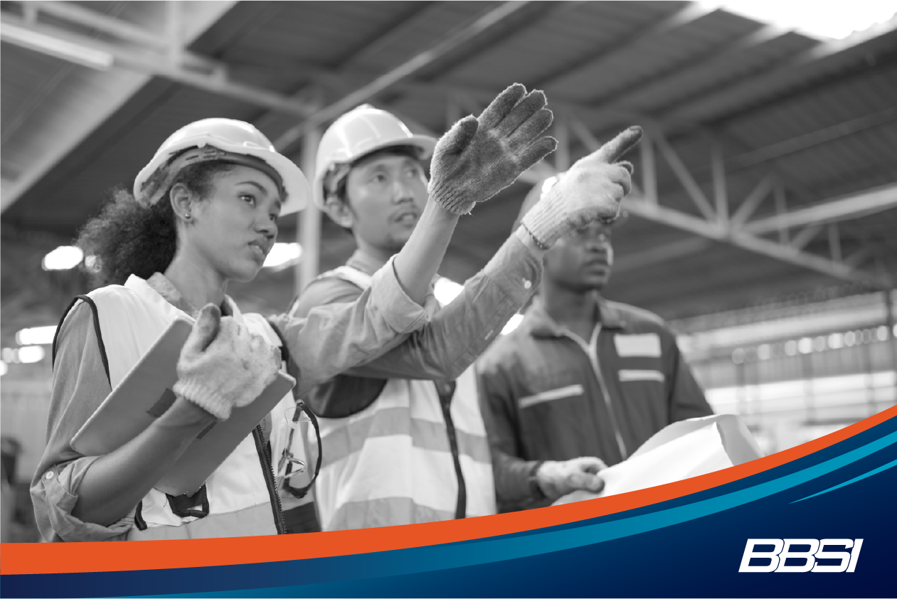 A group of construction workers, two men, and one woman, are discussing changes that need to be made to create a safer work environment