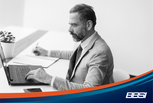 Man at a desk on his laptop taking notes