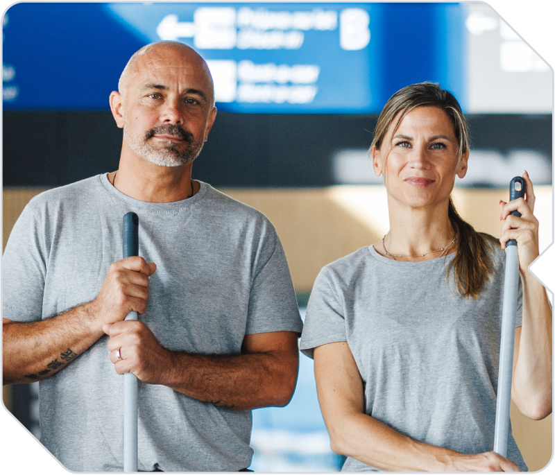 Two janitorial workers holding mops on a commercial jobsite.