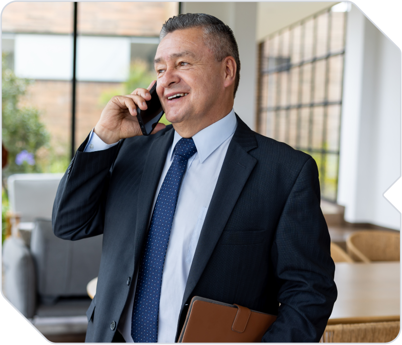 A real estate agent on the phone with his client at his brokerage.
