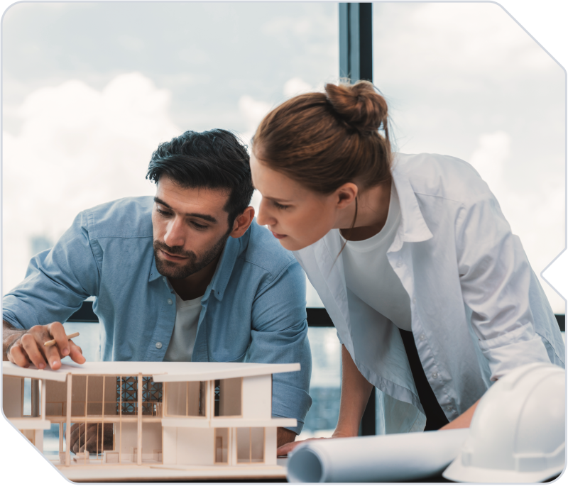 Two architects working on a building design model.