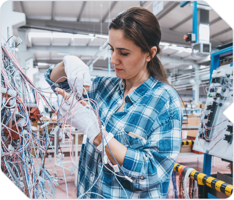 An employee inspecting power sources in a manufacturing warehouse.