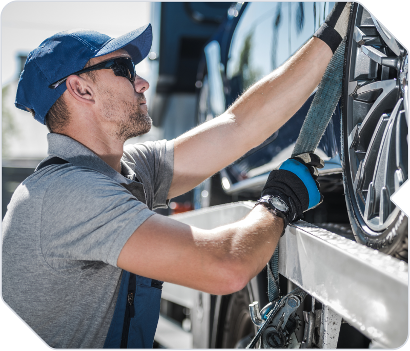 A towing company employee securing a car to a tow truck.
