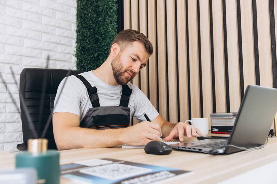 Mechanic business owner working at desk using HRIS Software