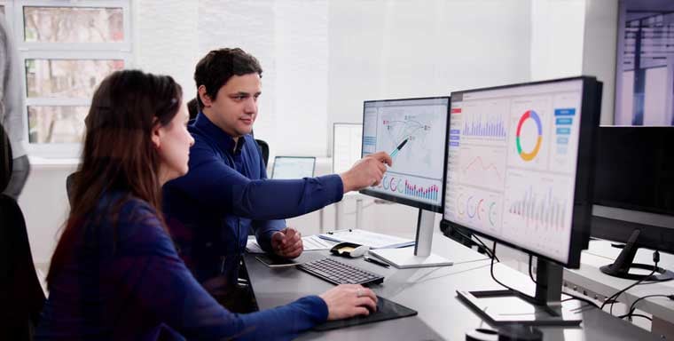 Two professionals exploring payroll and compliance charts on their computers