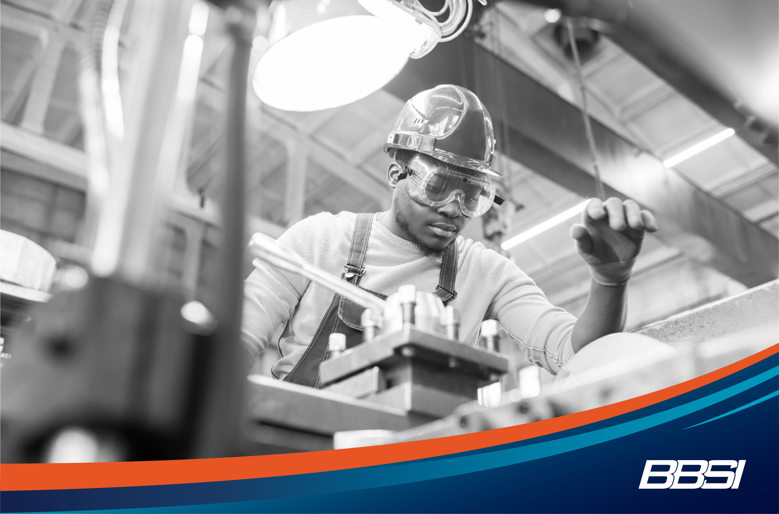 Man wearing safety glasses and hard hat, working at a machine