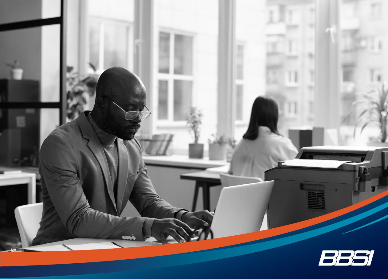 a business owner sitting at a laptop researching employee payroll solutions