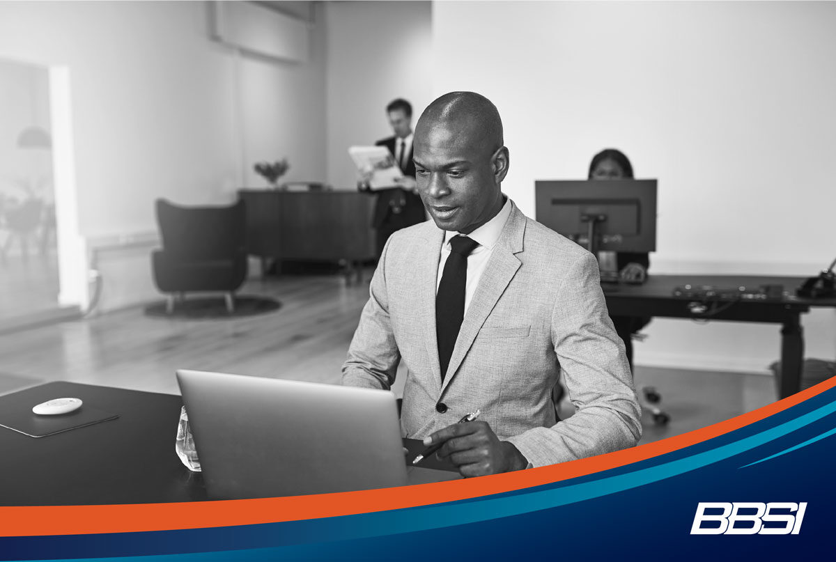a business owner working on a computer in a modern office researching PEO companies