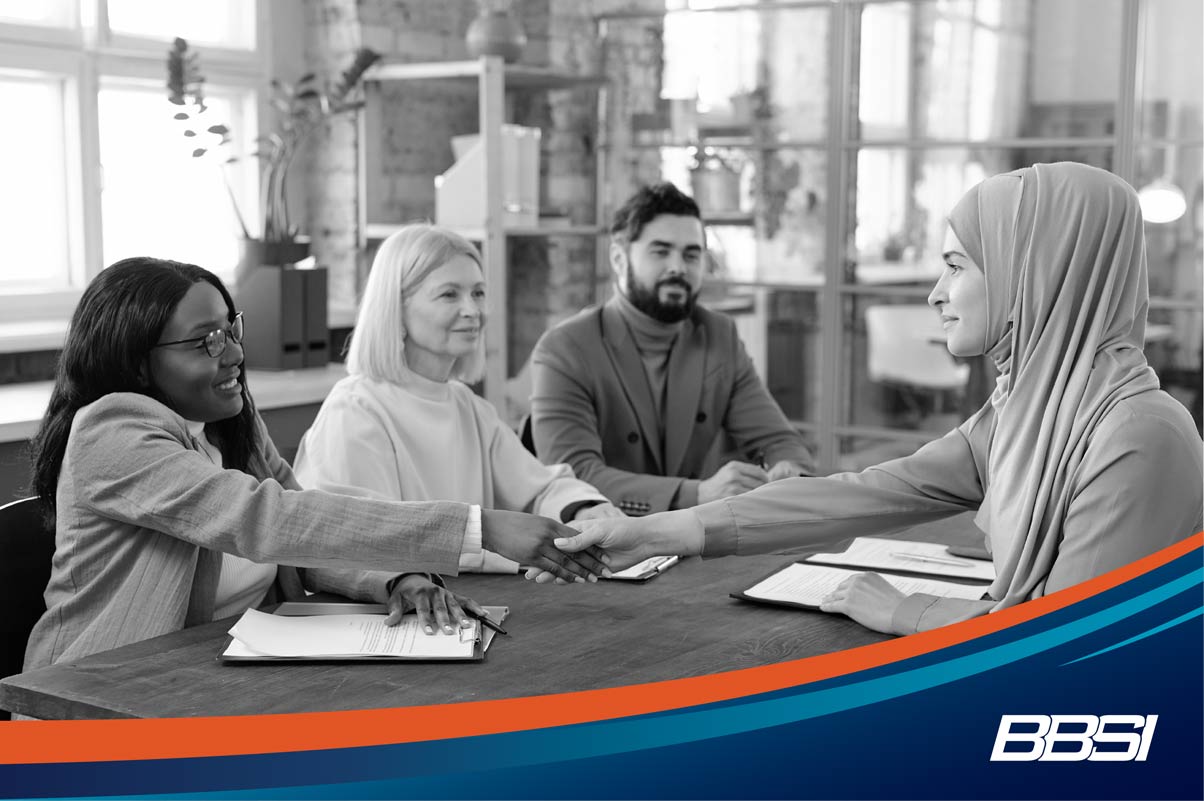 Two women shake hands during an interview after one woman is hired as a new employee