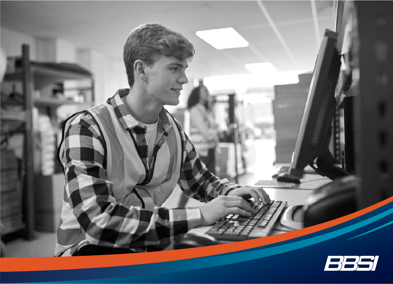 a young man in a warehouse at a computer using hr technology