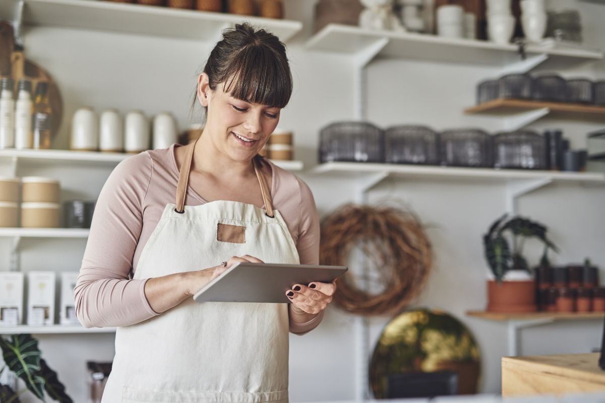 Business owner doing her company payroll on a tablet in her shop