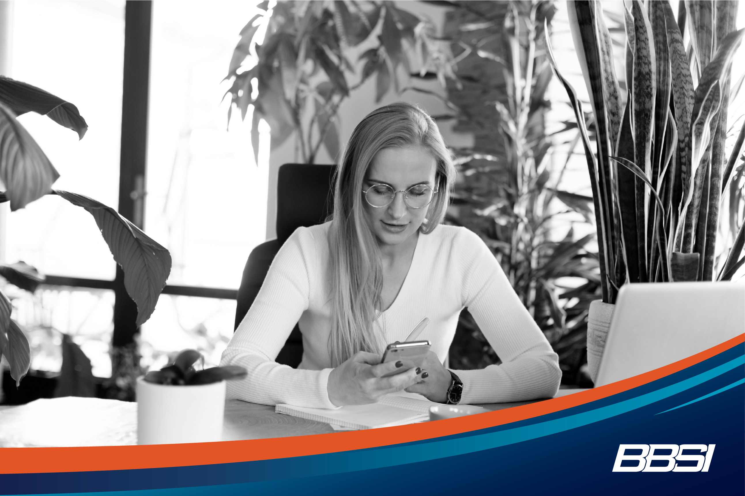 Woman sitting at her desk working on her phone, there are a lot of plants surrounding her desk