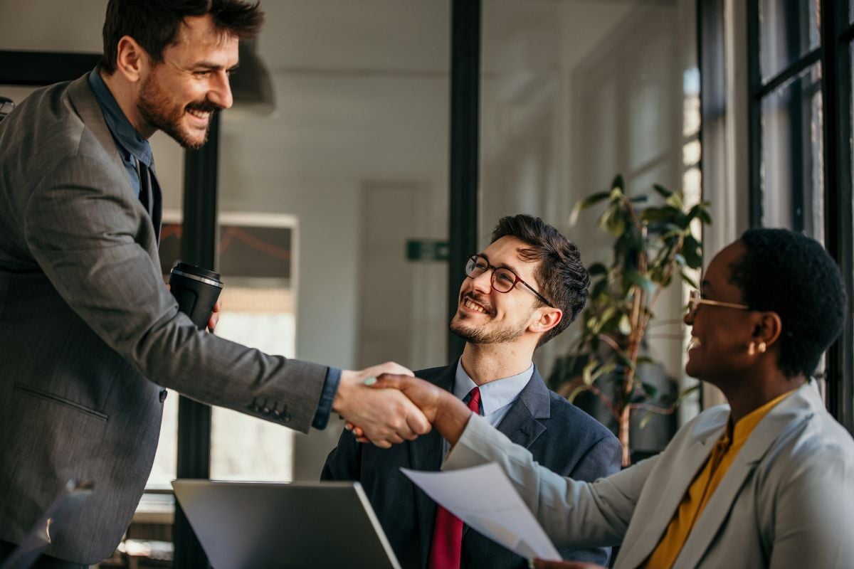 PEO representative and business owner shaking hands in a modern office