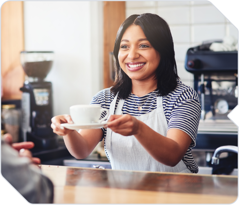 A barista handing a drink to a customer at a coffee shop.