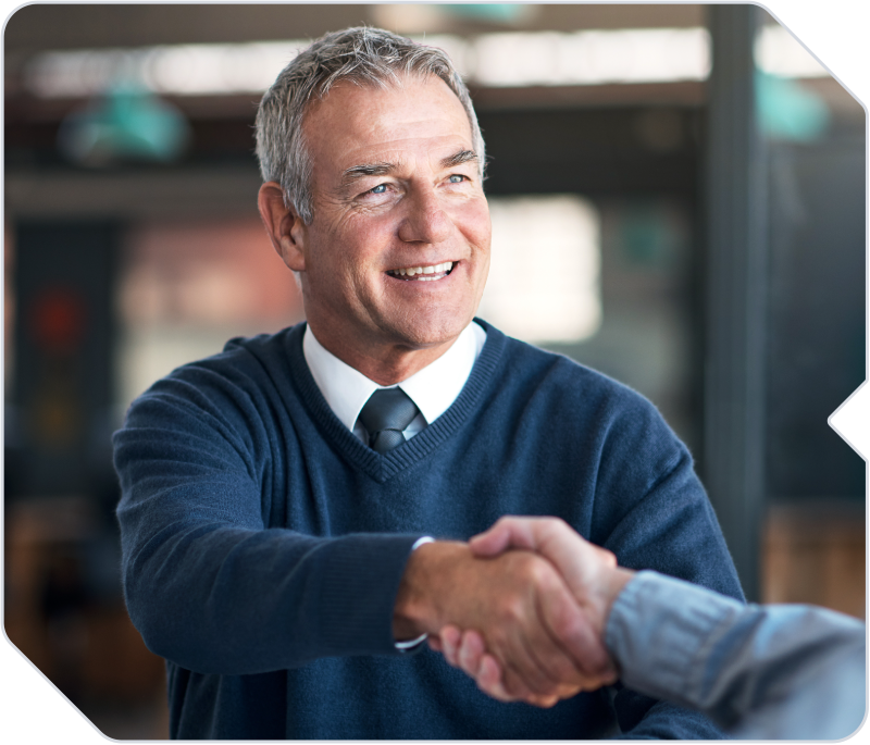 A broker shaking hands with a client at his insurance agency.