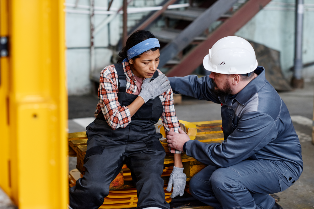 Colleague checking on an Injured factory worker