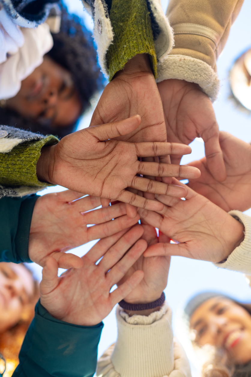 Group of diverse volunteers joining hands in a circle